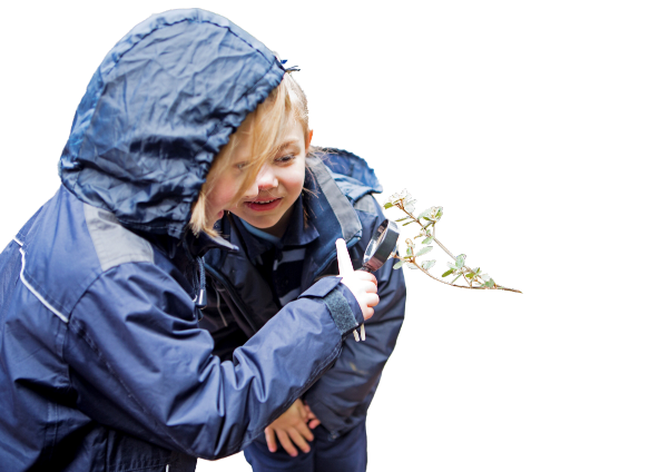 A blonde woman with a boy looking at a branch with a magnifying glass. Both are wearing blue rain jackets
